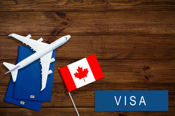 Visa to Canada concept. Text visa near passport cover and canadian flag, hammer on dark wooden...