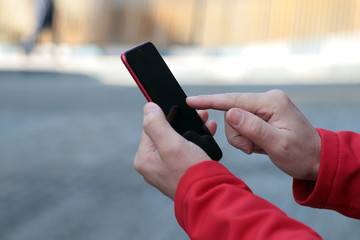 Young man holds a mobile phone with his hands .