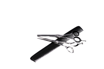 Two hairdressing scissors and a comb on a white background