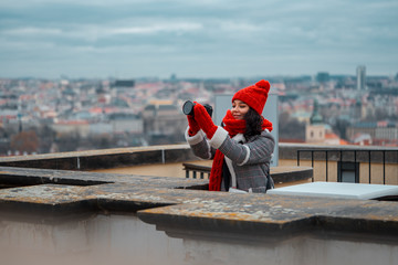 Wide Shot Of Young Attractive Woman With Big Red Scarf Making Photos Of Romantic View To The Gothic Cityscape of Prague.