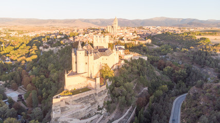 Obraz premium Historic medieval Castle in Segovia, Spain. Drone aerial view with sunset light of spanish stronghold in old town with monument cathedral. History prison, alcazar of Segovia, world heritage.