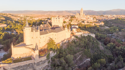 Fototapeta na wymiar Historic medieval Castle in Segovia, Spain. Drone aerial view with sunset light of spanish stronghold in old town with monument cathedral. History prison, alcazar of Segovia, world heritage.