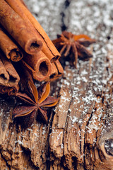 Christmas setting with bundle of cinnamon, anise stars and other christmas decorations on the rustic wooden background. Selective focus. Shallow depth of field.