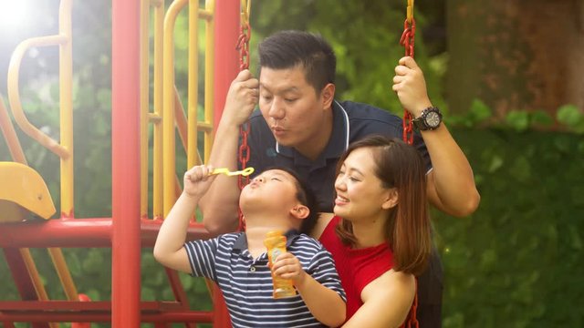 Child and parents playing soap bubbles at summer