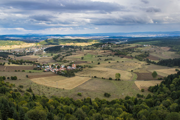 Fototapeta na wymiar Panoramic view of green and yellow fields, green forest, blue mountain, clouds, small town and road