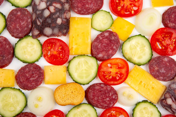 sliced ​​pieces of sausage, salami, cheese, cucumber and tomato. fast food. ingredients for pizza. calories and diet