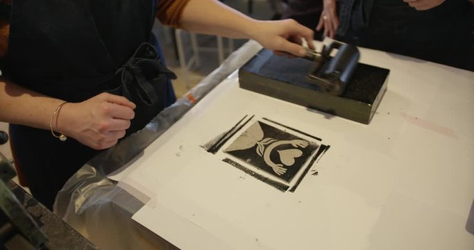 hand rolling ink on to the ink roller. rolling ink on the lino cutout art design. rolling ink out on a block. making artwork.