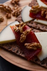 Wood plate with cheese, nuts and quince jelly on top of toasted bread. Healthy food. 