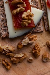 Wood plate with cheese, nuts and quince jelly on top of toasted bread. Healthy food. 