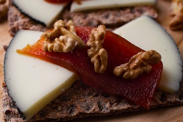 Wood plate with cheese, nuts and quince jelly on top of toasted bread. Healthy food. 