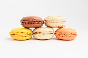 Close up of row of five sweet French macarons with different aromas, isolated on white, flavours of orange, lemon, caramel, vanilla and coconut pastel colors of freshly tasty dessert