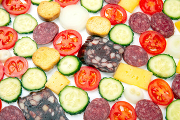 sliced ​​pieces of sausage, salami, cheese, cucumber and tomato on a white background. fast food. ingredients for pizza. calories and diet