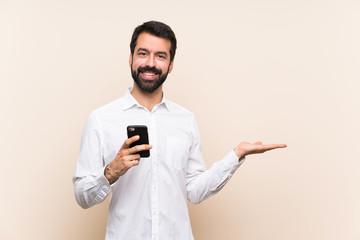 Young man with beard holding a mobile holding copyspace imaginary on the palm to insert an ad