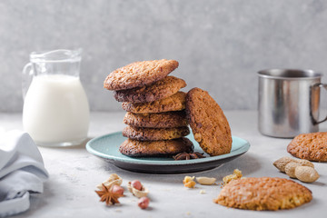 Homemade organic oatmeal cookies with peanuts  and bottle of milk on light concrete background.