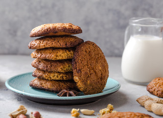 Homemade organic oatmeal cookies with peanuts  and bottle of milk on light concrete background.