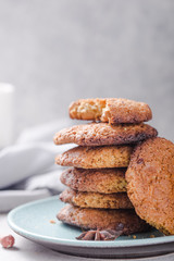 Homemade organic oatmeal cookies with peanuts  and bottle of milk on light concrete background.