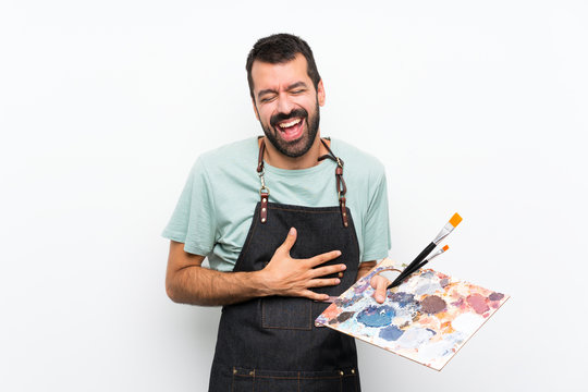 Young artist man holding a palette over isolated background smiling a lot