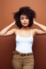 pretty young african american woman with curly hair posing cheerful gesturing on brown background, lifestyle people concept