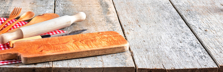 Kitchen utensil tools including cutting board, knife and spoons with rustic wooden background. Top...