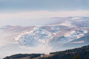 Obraz premium Terraced field in the valley at wintertime, dense fog, view from the top of a mountain in the Carpathian mountains.