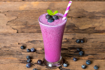 Blueberry smoothie purple colorful fruit juice milkshake blend beverage healthy high protein the taste yummy In glass drink episode morning on wooden background.