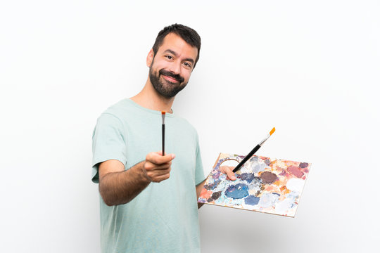 Happy Young artist man holding a palette over isolated background