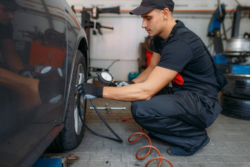 Auto mechanic checks the tire pressure in service