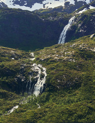 Northern landscape with mountains and forest at the foreground and mountain peak and waterfall on the background. Senja Island, Troms County, Norway.