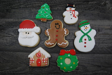 Seven Iced, Decorated Christmas cookies on wood flat lay