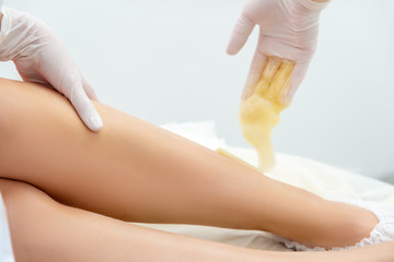 beautician hair removal procedure on the client's feet in beauty parlor