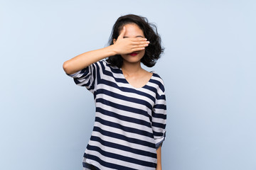 Asian young woman over isolated blue background covering eyes by hands. Do not want to see something