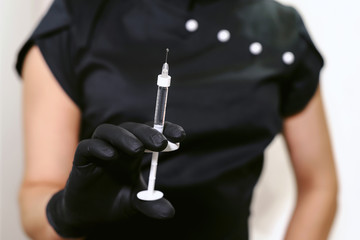 Portrait of beauty doctor. Beautiful young woman beautician in black medical uniform holding...
