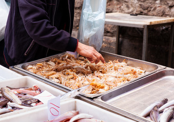 Salesman selling sea cicadas in the street fish market, Catania