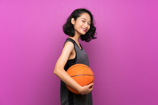 Young Asian Woman Playing Basketball Over Isolated Purple Background