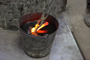 After forging, the molten metal billet is cooled in a bucket of engine oil
