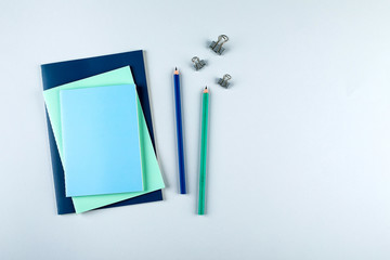 Blue and green notebooks with stationary objects on the grey background