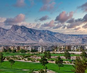 Fototapeta na wymiar A golf course by a condo complex in front of a mountain range