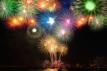 Fototapeta na wymiar Beautiful color fireworks Show in the dark sky in the sea, close to the beach at the city of tourism. Happy New Year 2020