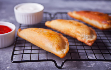 Mexican fried meat pies empanadas cheburek on the baking rack with dips.