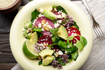Top view at mediterranean roasted beet salad with avocado walnuts feta cheese oregano and mash leaves on dinner table