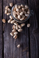 Pistachios in glass jars on a wooden background