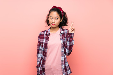 Asian young woman over isolated pink background with fingers crossing and wishing the best