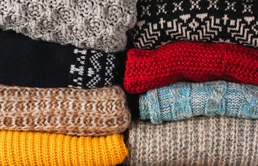 Stacks of woolen knitted clothes in a wardrobe.