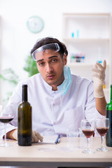 Male chemist examining wine samples at lab