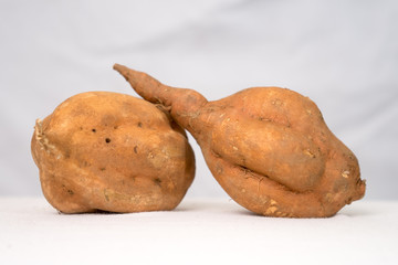 Two sweet potato tubers (Ipomoea batatas) on white background