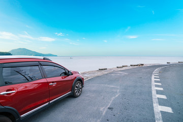 Modern new red SUV car on the road with Summer sea background of free space for summer text and travel transportation background