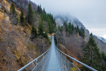 A simple suspension bridge in the mountains, suspended or hanging bridge - Image