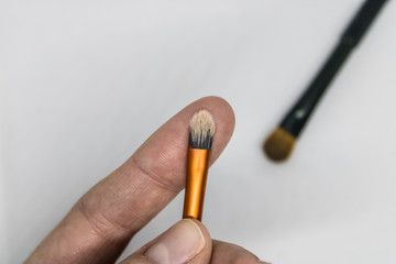 Woman hand holding an eye detailer brush with another makeup brush on the background - Image