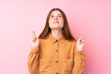 Ukrainian teenager girl over isolated pink background with fingers crossing and wishing the best