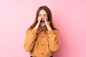 Ukrainian teenager girl over isolated pink background shouting and announcing something